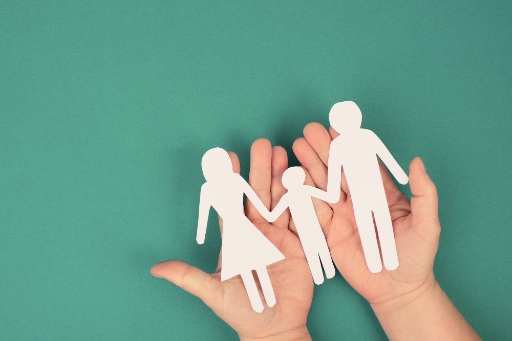 Parents with one child holding hands, paper cut out, copy space, petrol colored background Parents with one child holding hands, paper cut out, copy space, petrol colored background